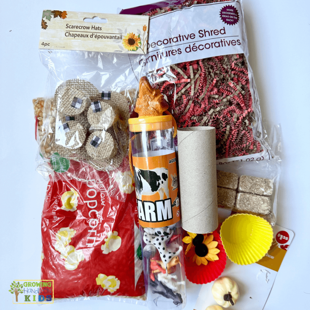 Farm animal sensory bin materials featuring plastic farm animals, corn kernels, sunflowers, shredded paper, and small toys. 