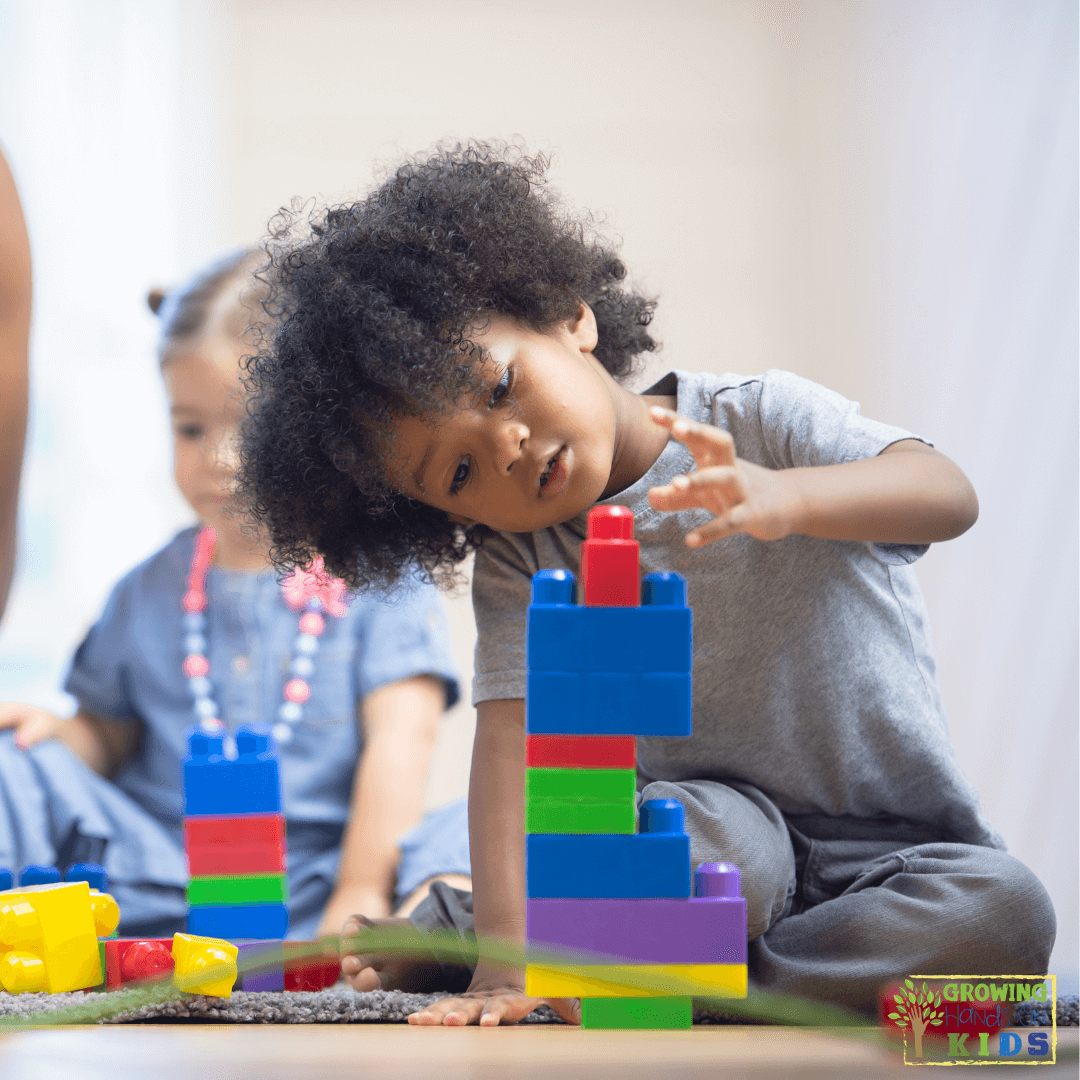 Young child focused on stacking colorful building blocks, developing fine motor skills, with another child in the background engaging in play.