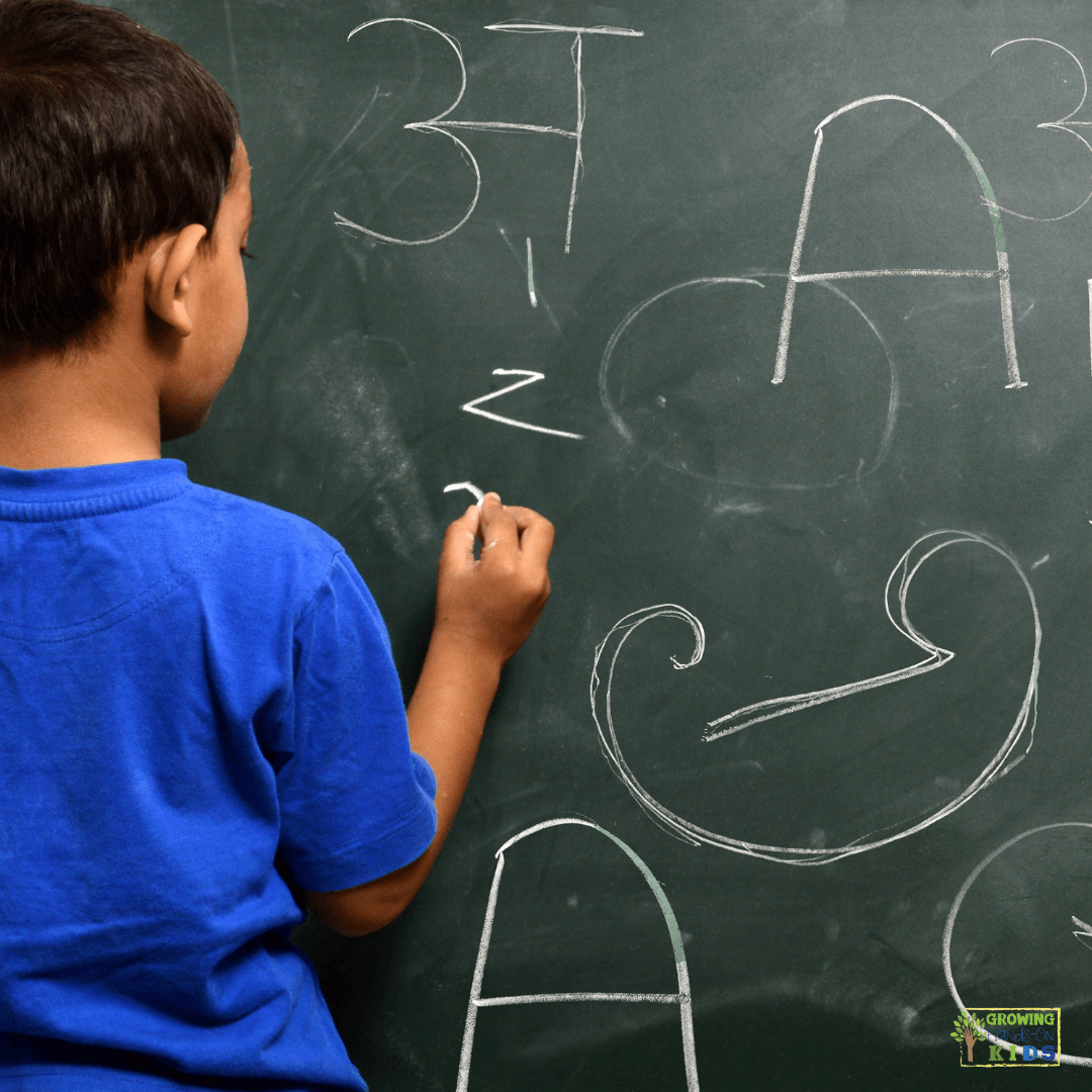 Child practicing handwriting on a chalkboard, engaging in vertical surface activities to develop fine motor skills and improve handwriting abilities.